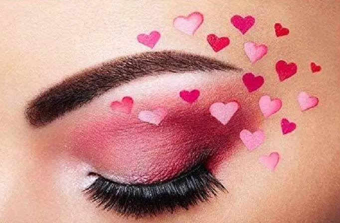 Close-up of a woman's eye with pink makeup and heart-shaped stickers.